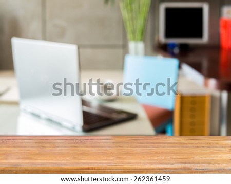 Wooden table top over blurred image of  modern workplace background