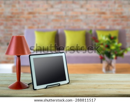 Red lamp, tablet on wooden table top with modern Living room blurry background