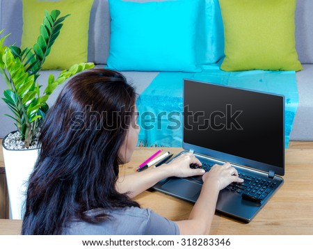 Casual woman working with laptop computer near couch in modern Living room
