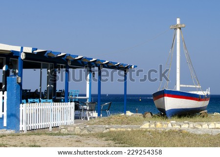 Traditional blue and white Greek  tavern restaurant with sea view and a boat, Greece,Kos.