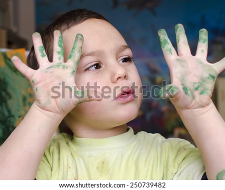 Portrait of a child boy  painting a colorful abstract picture with a brush and poster paint colors.