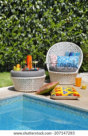 white rattan chair and pillows by swimming pool