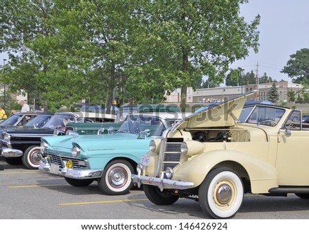 ANCASTER, ON, CANADA - JUNE 19: unnamed spectators looking at the vintage cars displayed at weekly Oldtimer meet at the local shopping mall June 19, 2012 in Ancaster Ontario Canada