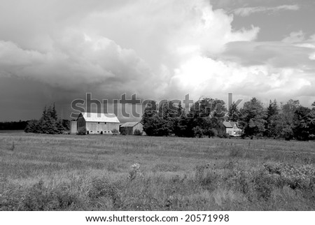agricultural building surrounded by farmland and storm clouds