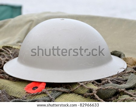 close up of a symbol of remembrance the Remembrance Poppy lying beside a military helmet