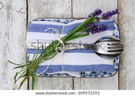 silver cutlery on a blue white saucer plate and napkin with lavender decoration and empty copy space in vintage country style