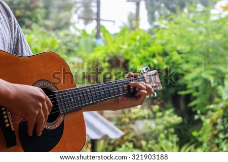Man playing an acoustic guitar in the garden