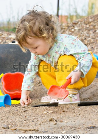 child plays with sand in the park