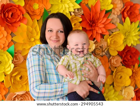 happy smiling young mommy hugging her laughing funny baby son on ornamental flowers background