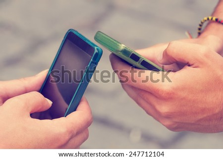 Couple looking at their smart-phones in the park.