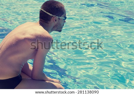 Swimmer taking a rest at the edge of a pool.