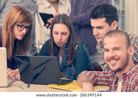 Young group of people discussing business plans. Optical focus on the right smiley guy.