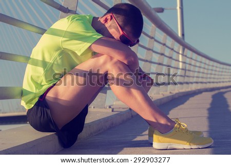 Tired urban jogger making a pause a big bridge.