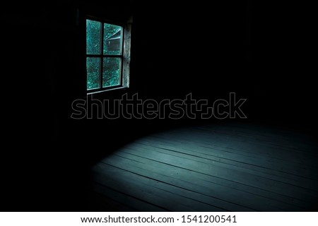 Abstract horror background for halloween. Gloomy scary terrible window with ghostly light and shadows in a dark black room in the attic, corridor or basement in an abandoned house in the forest
