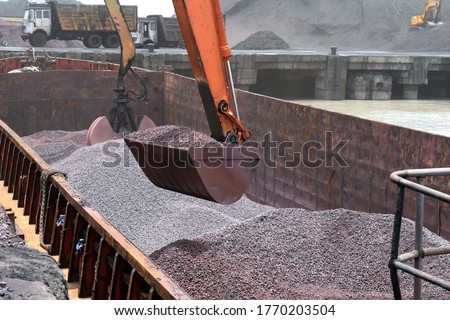 Crane Lifting Iron Ore From the Barge at Dindayal Port Kandla India. Iron Ore Imported from Australia. Big Hydraulic Grabs of Crane at work  Imagine de stoc © 