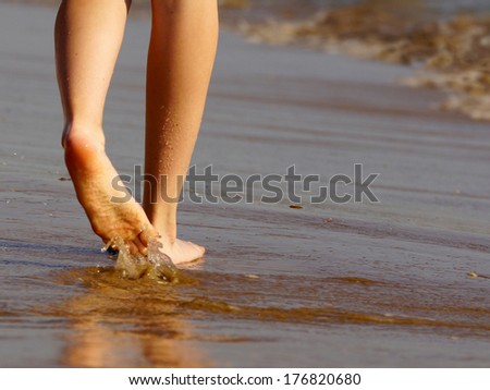 female legs in motion on wet sea sand.