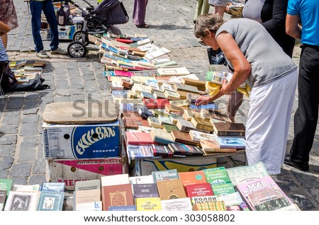 Lviv, Ukraine - CIRCA July 2015: Men and women choose and buy, and sellers are selling old rare books and vintage items in the book market near the monument to Fedorov in Lviv, Ukraine