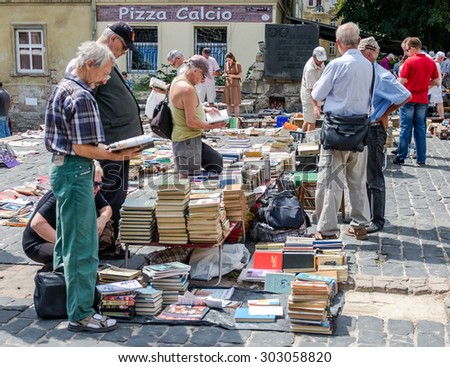 Lviv, Ukraine - CIRCA July 2015: Men and women choose and buy, and sellers are selling old rare books and vintage items in the book market near the monument to Fedorov in Lviv, Ukraine