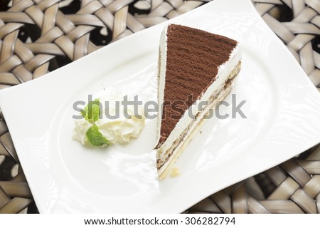 tiramisu cake served with whipped cream in the white dish