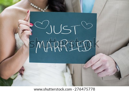 Bride and Groom holding small blackboard with message Just Married