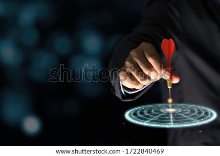 Businessman throwing red arrow dart to virtual target dart board. Setup objectives and target for business investment concept.