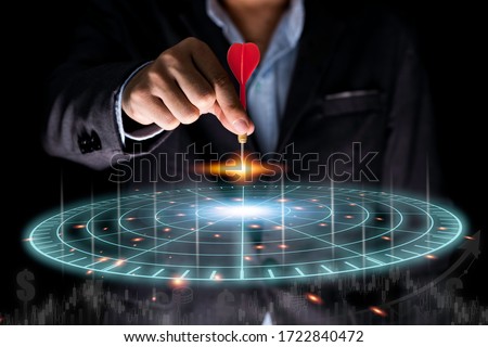 Businessman throwing red arrow dart to virtual target dart board. Setup objectives and target for business investment concept.
