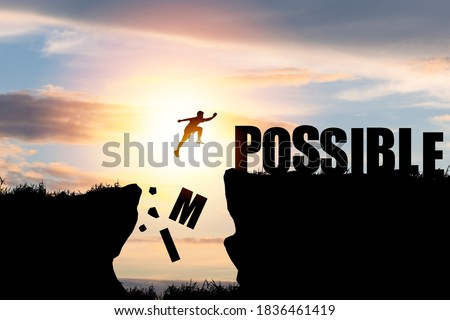 Mindset concept ,Silhouette man jumping over impossible and possible  wording on cliff with cloud sky and sunlight.