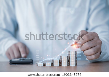 Businessman hand drawing virtual increasing graph with money coins stacking , Business investment profit and deposit dividend saving growth in 2021 concept.