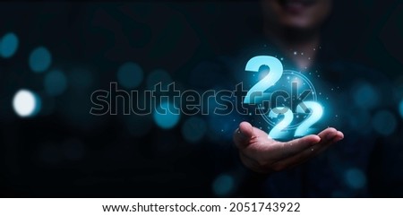 Businessman holding virtual 2022 number with blue bokeh background and copy space for merry Christmas and happy new year concept.