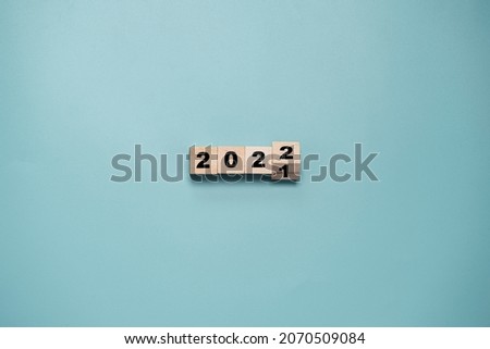 Wooden cube block flipping from 2021 to 2022 on blue background , preparation for merry Christmas and happy new year and 3d rendering concept.