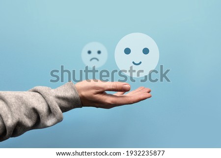 A sad and joyful face in the hand of a man. Choosing between the negative and the positive in a person's life