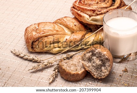 Variety of baked goods, glass of milk and wheat ears on the table