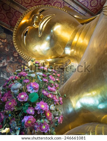 Golden Buddha image head close up with flowers in the foreground
