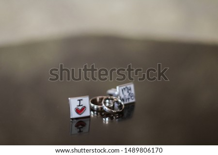 traditional gold bride and groom wedding rings and cufflinks on a glossy table.