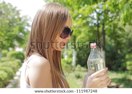 Portrait of beautiful smiling woman with bottle of water, outdoors, summer