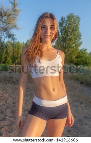 A portrait of a beautiful young Caucasian woman outdoor. Portrait of sporty blonde woman outside in the field in sport wear, front view