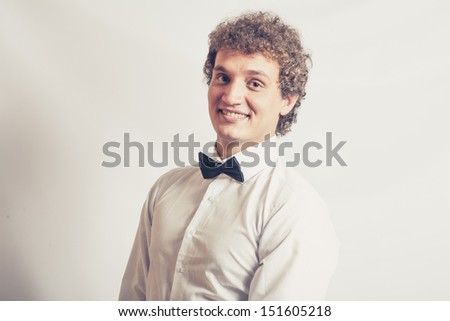 Toned image Fashionable boy smiling expression. Curly hair, white shirt. Bow tie for something funny