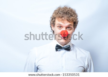 sad clown with red nose - curly man with bow tie head and shoulders shot looking at camera