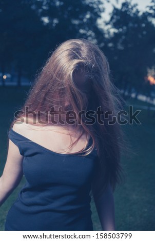 Toned image. Face is hidden by hair. Sad 20s female outside close-up image. Portrait of a beautiful young 20s women in the park in evening.