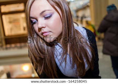 Closeup shot of the Female looking down with blank expression on the face. Photo of young beautiful lady inside the big mall