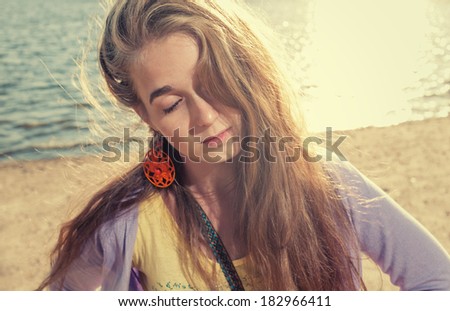 Mysterious girl alone on aseashore with her eyes closed