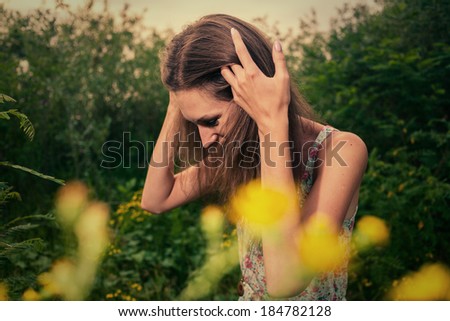Pretty blonde in a summer field looking down toned image