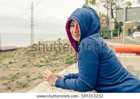 Women in hooded shirt outdoors looking at camera