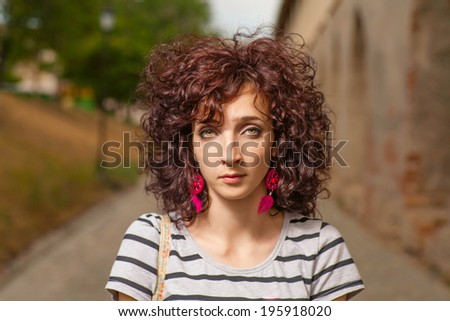 Serious girl looking at camera. Curly red haired women closeup shot
