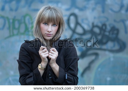 Blonde women against slums posing with blank expression on her face