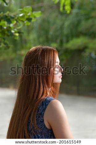 Side view of a red haired women outdoors with blank expression on her pretty face