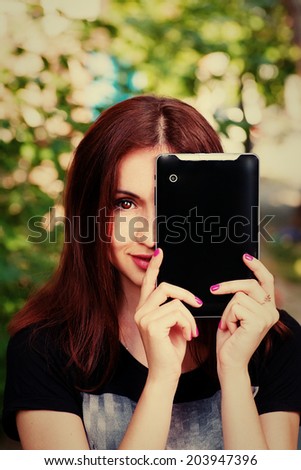 Young women hide her face by modern tablet computer and smiling wide