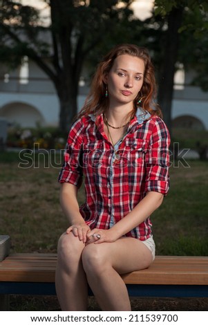 Sad red haired women on park bench