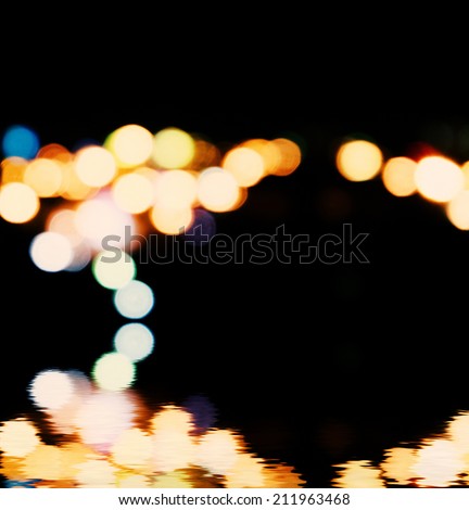 City lights in the background with blurring spots of  light reflected in water below
