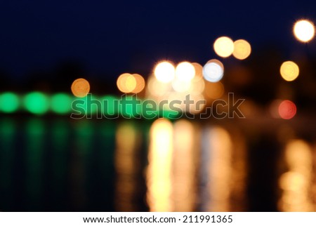 Blurred street lights and reflection in water background. Nightlife wallpaper, a lot of copyspace
